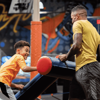 Child and parent smiling and boxing with foam blocks
